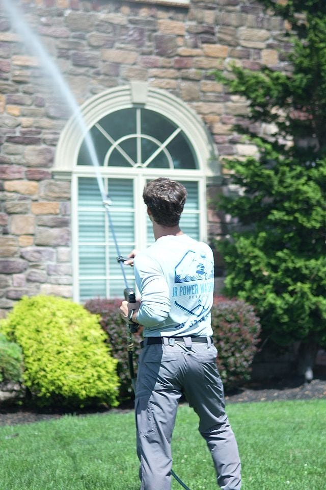 Soft washing the stone facade and arched window of a home